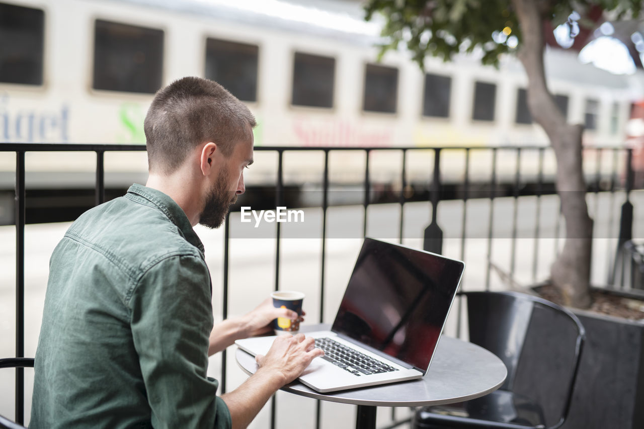 Man using laptop in outdoor cafe