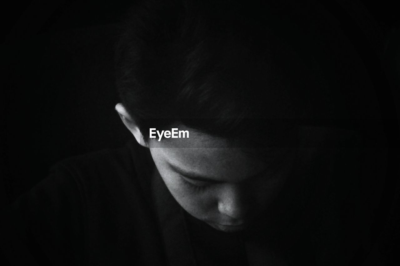 Close-up of thoughtful boy against black background