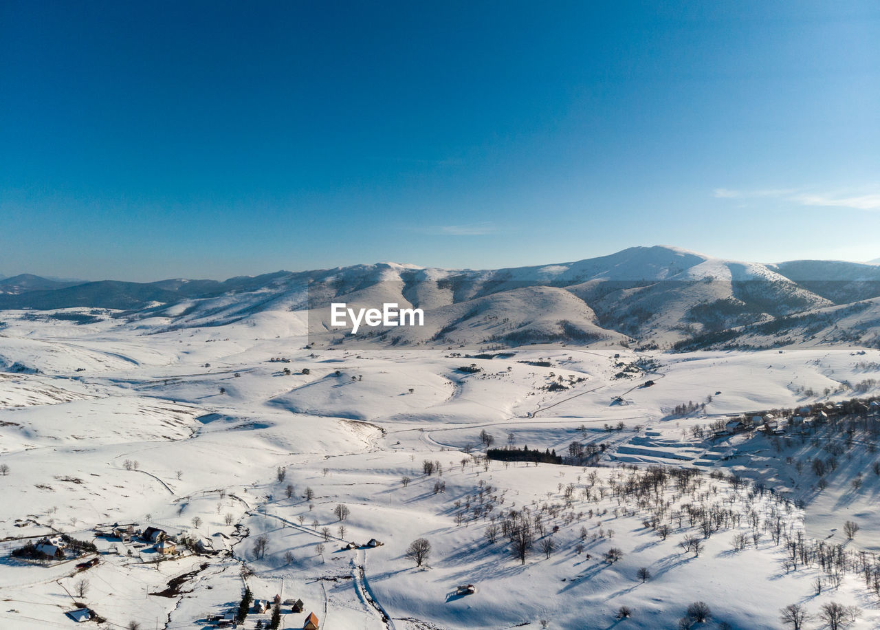 Scenic view of snowcapped mountains against clear blue sky