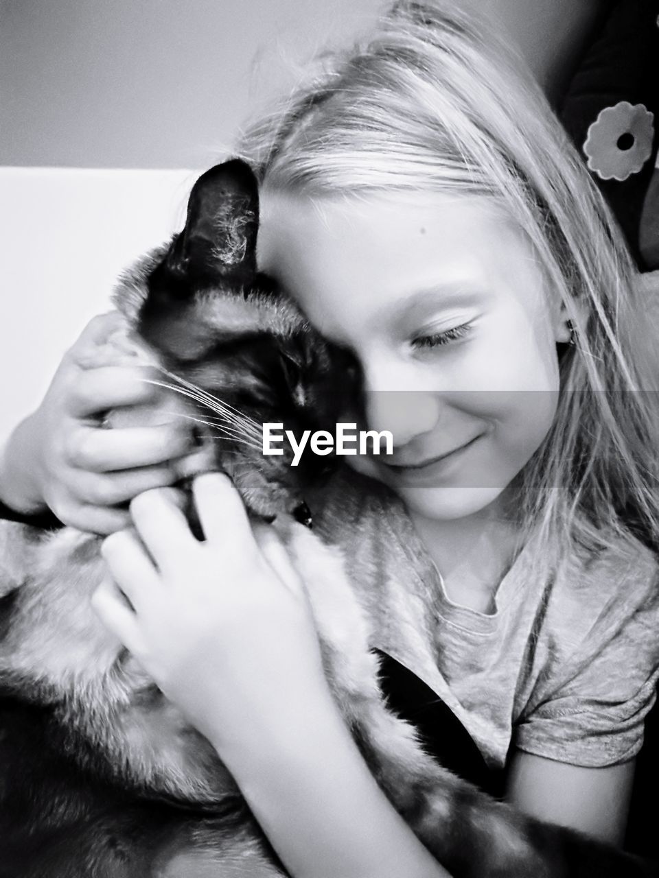 Close-up of smiling cute girl embracing cat at home