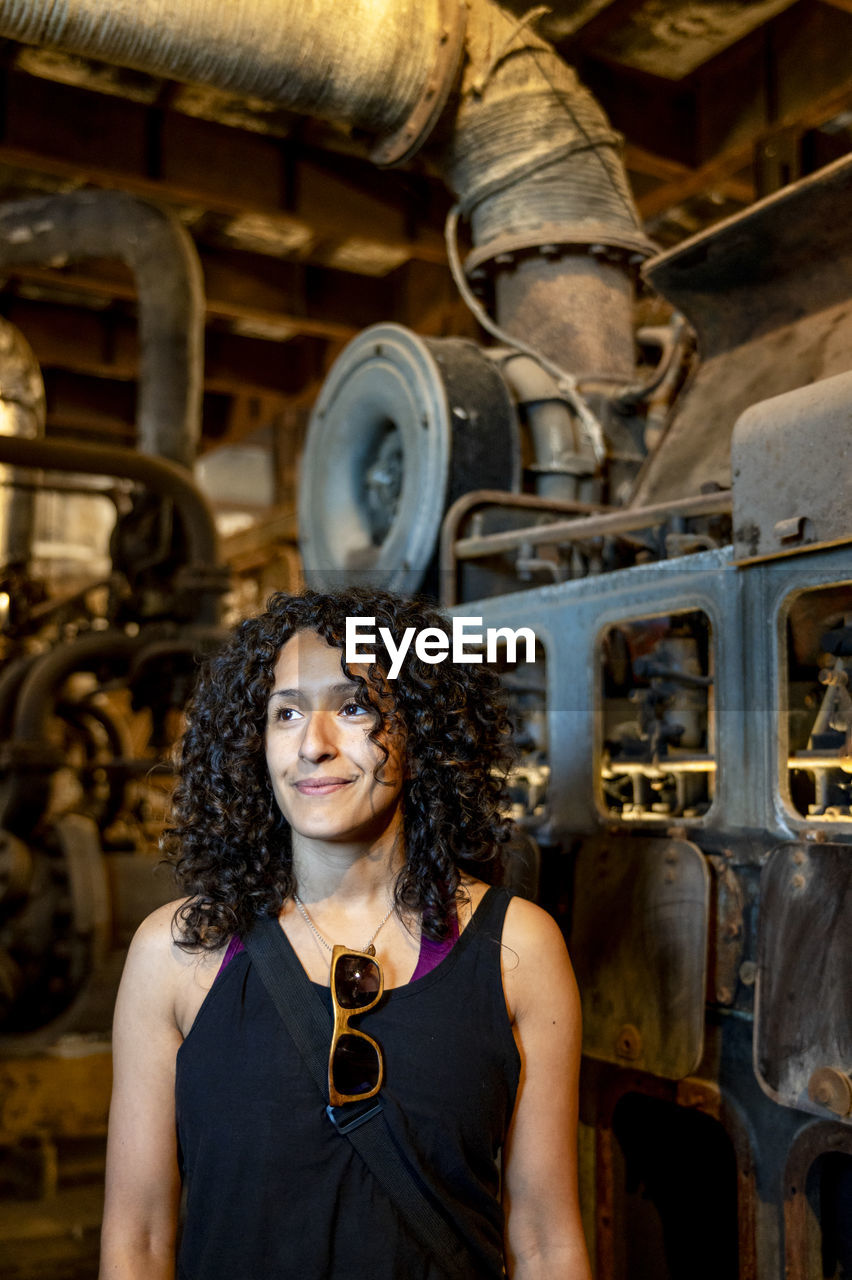 Portrait of a mixed race woman smiling while posing inside an abandoned factory.