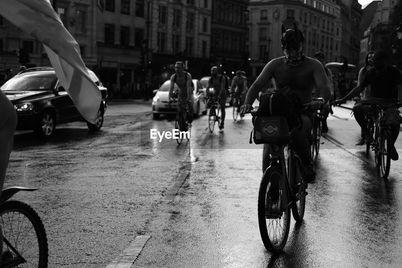 Shirtless man wearing devil mask while riding bicycle on street