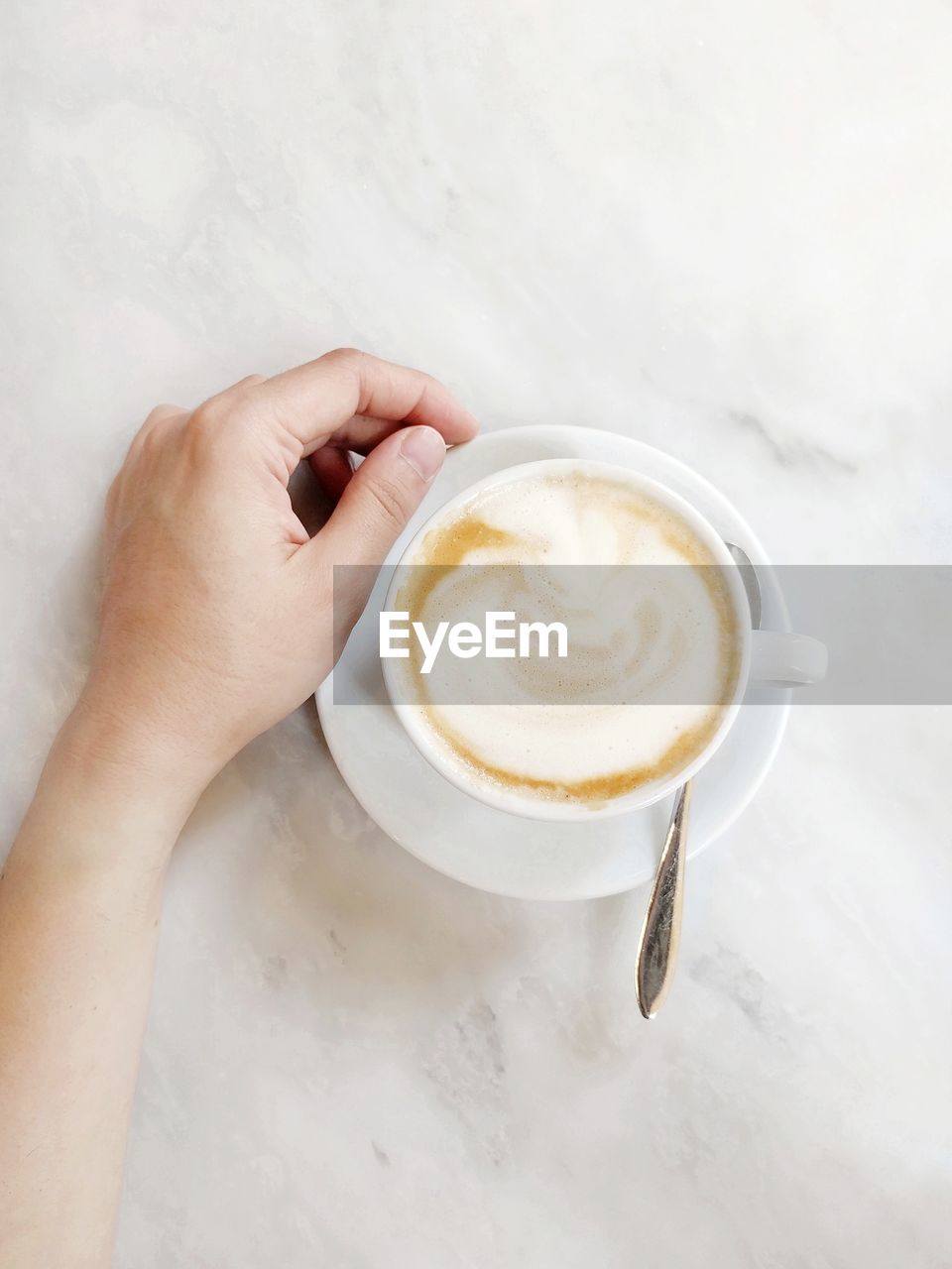 CROPPED IMAGE OF HAND HOLDING COFFEE CUP WITH CAPPUCCINO