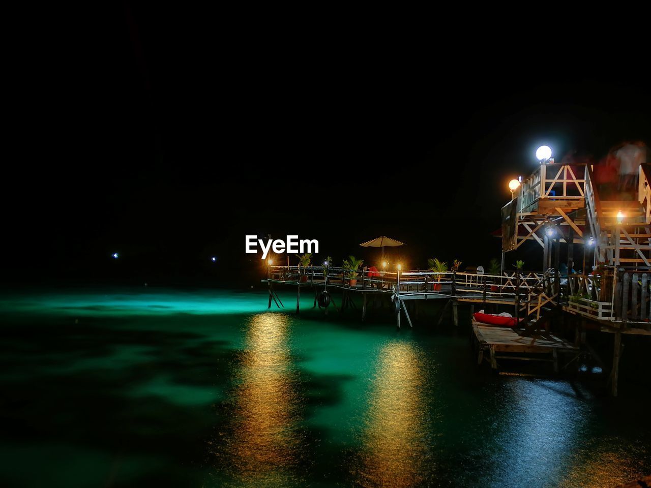 ILLUMINATED BOATS ON SEA AT NIGHT