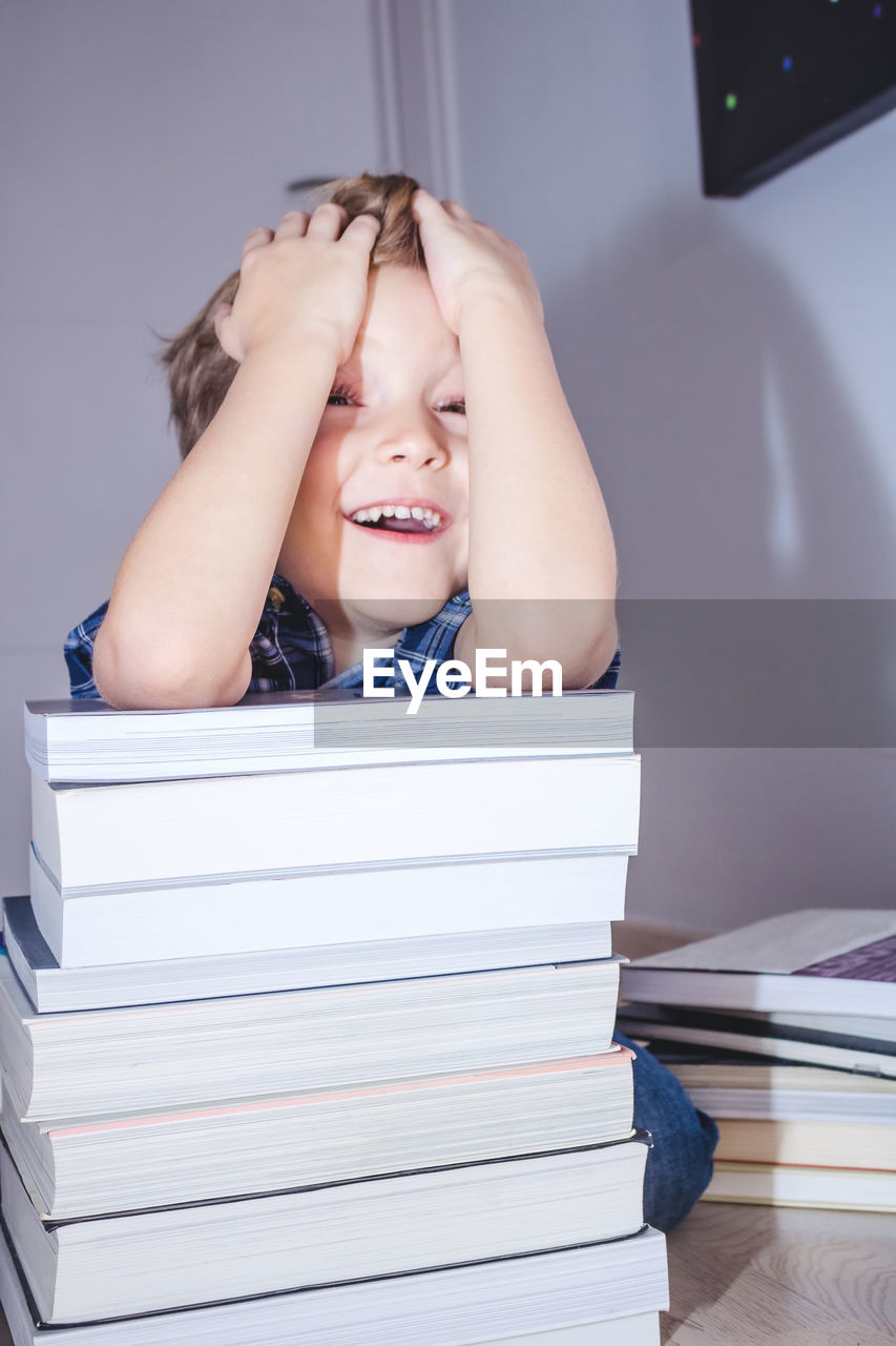 Smiling boy with books kneeling on floor at home