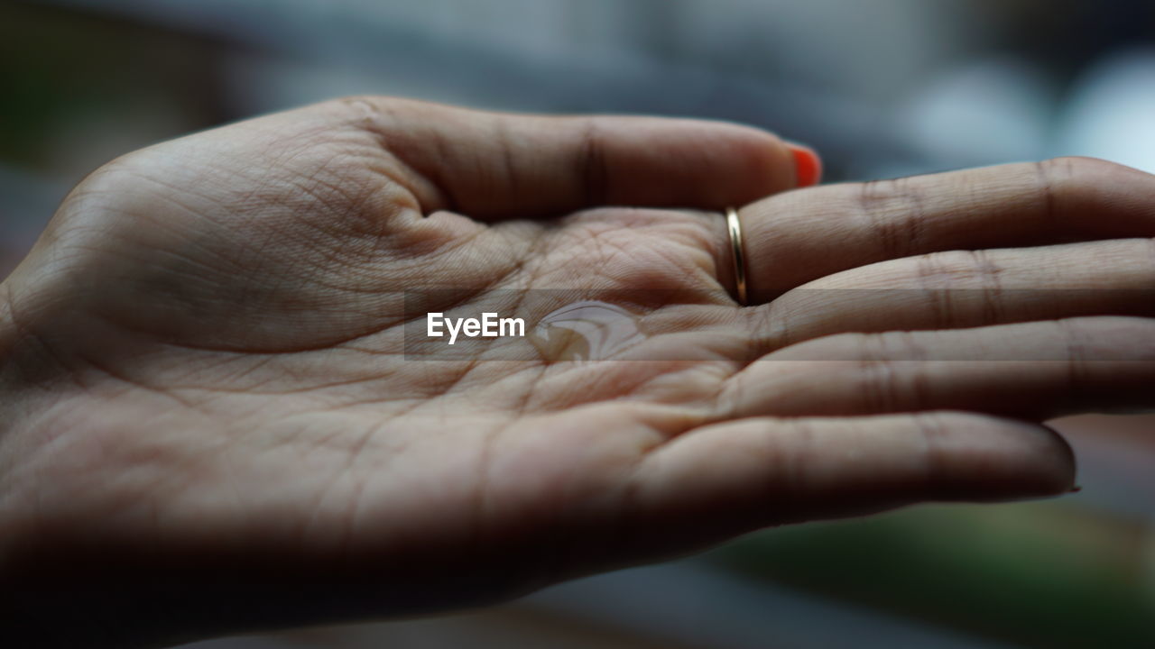 Cropped hand holding water drop