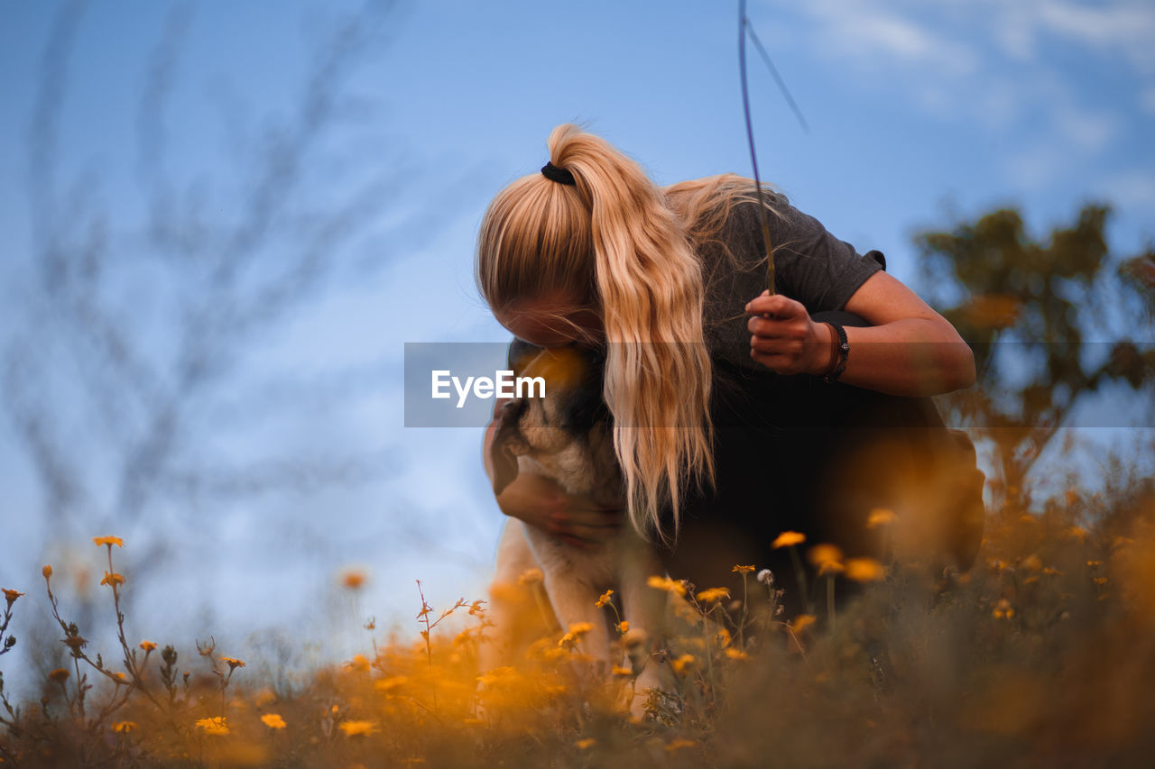 Woman with dog on field against sky