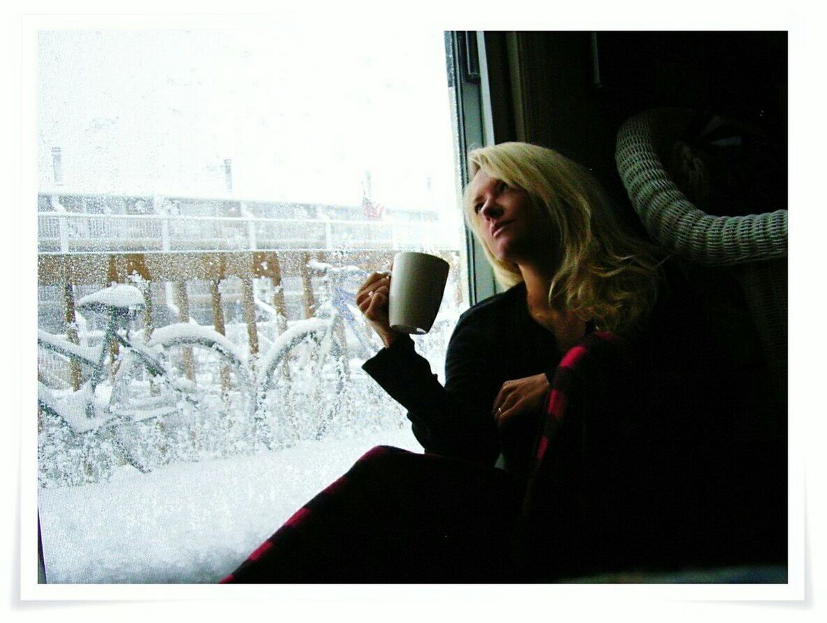 Woman sitting near door while having coffee at home during winter