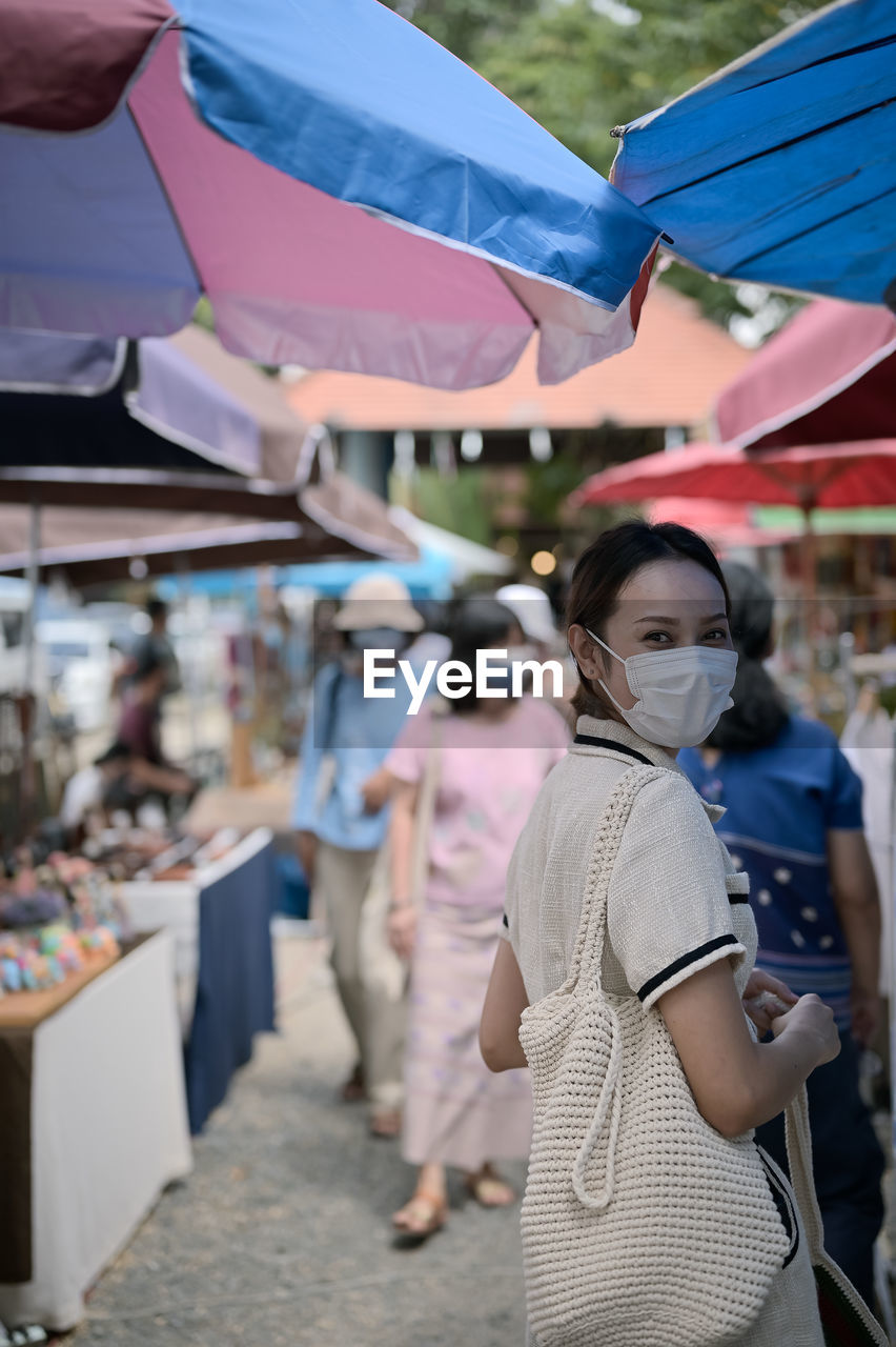 Young women wear surgical protection mask and carrying reusable bag walking in street market