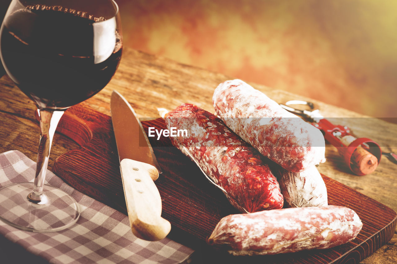 Close-up of red wine glass and salami on table