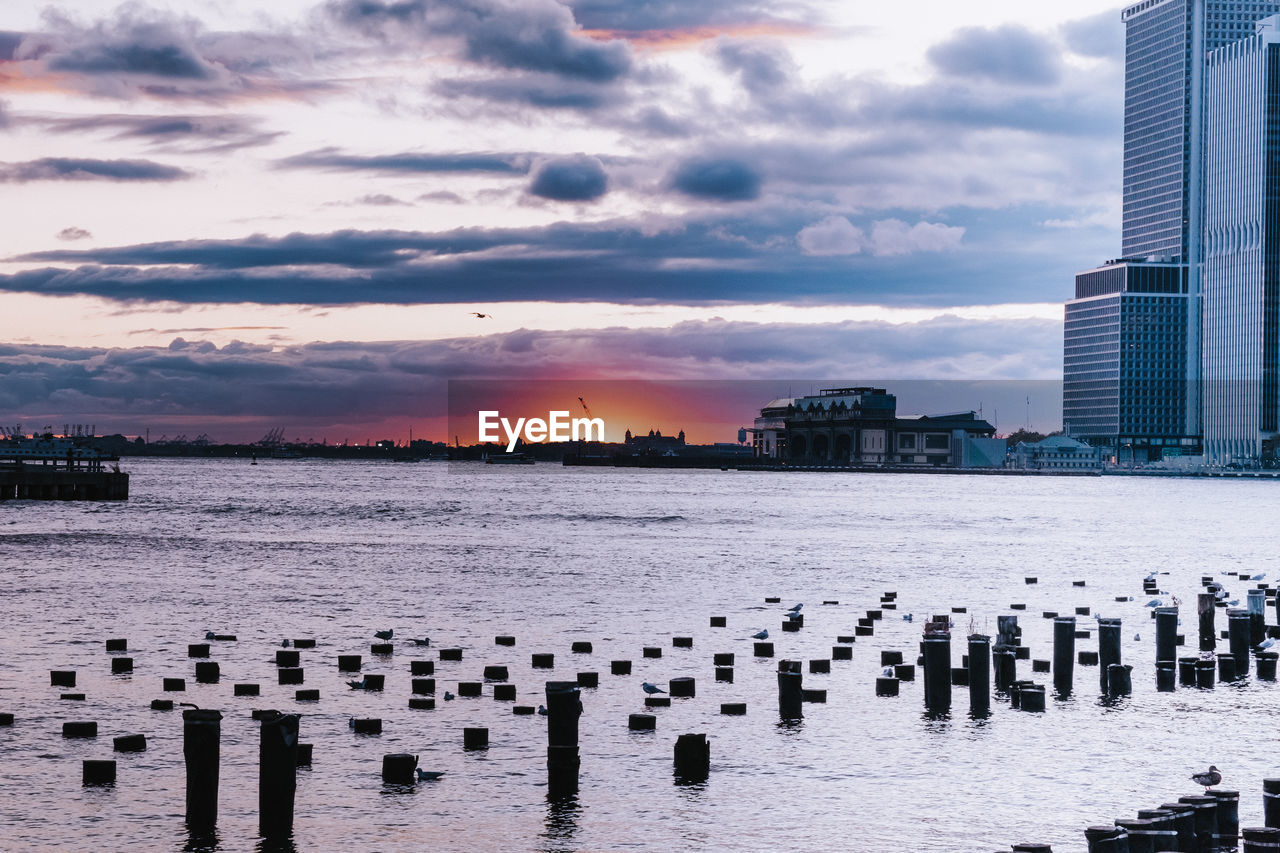 Scenic view of sea by buildings against sky during sunset