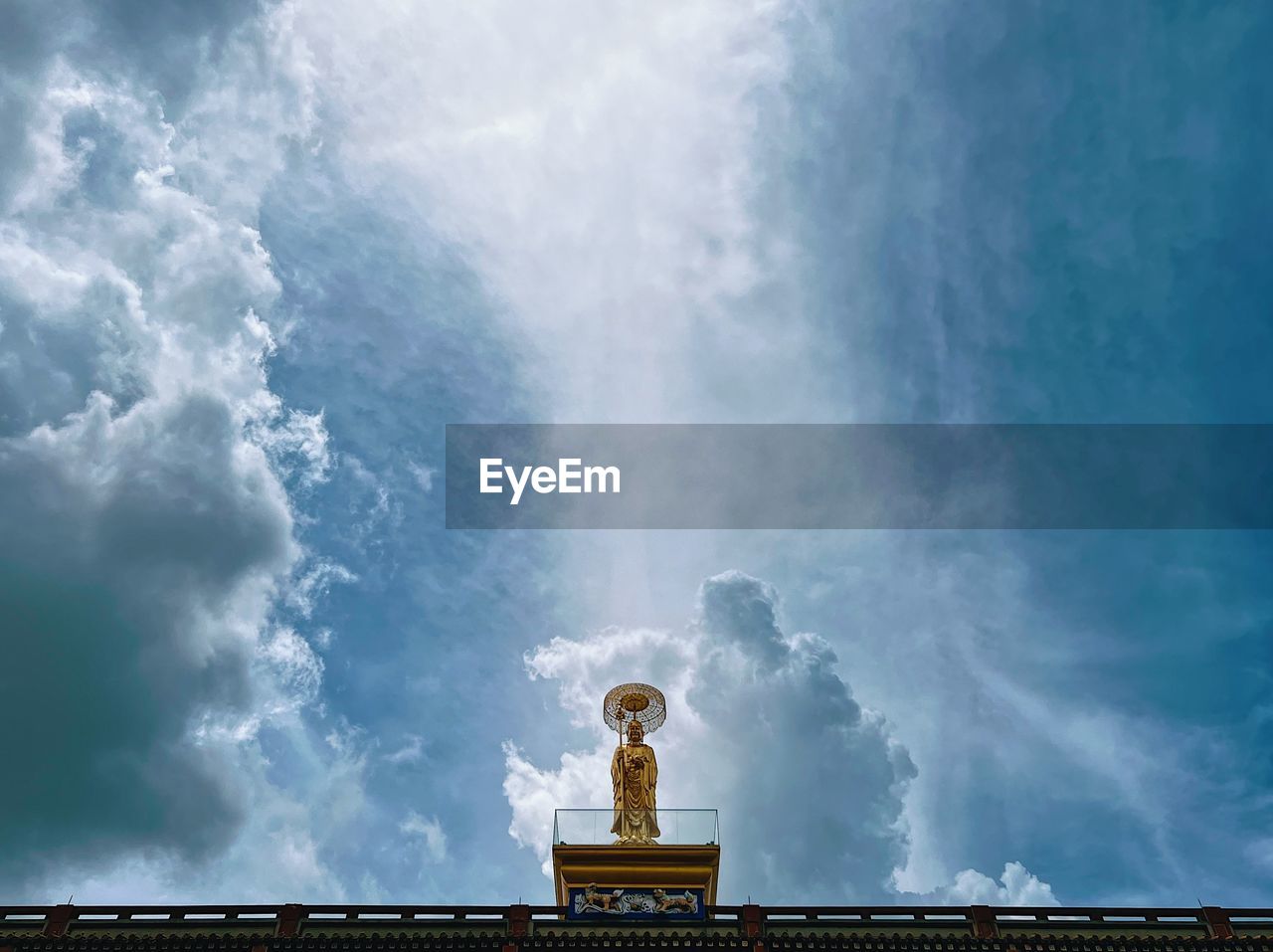 Low angle view of buddha statue standing against sky