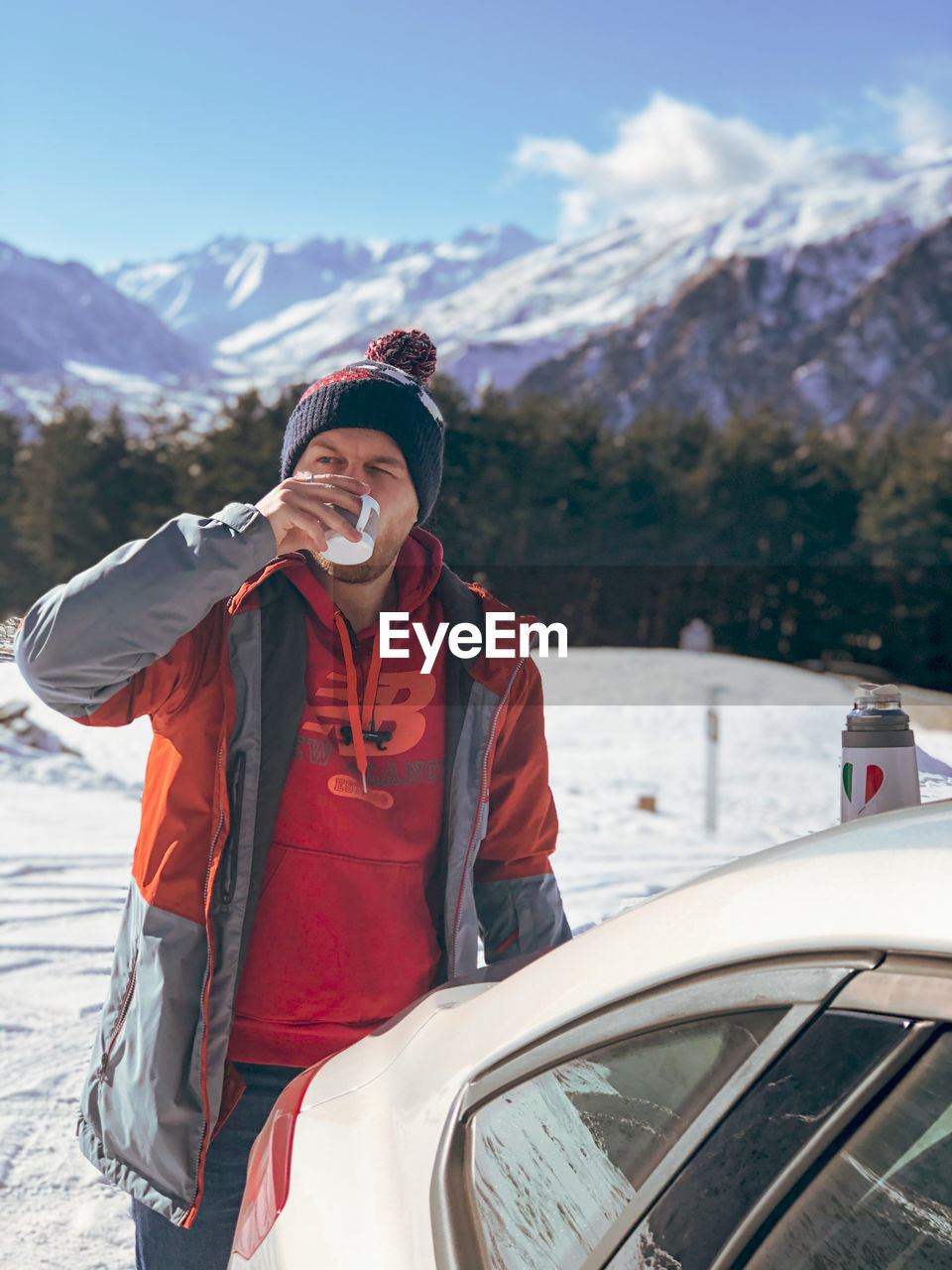 MAN WEARING HAT STANDING AGAINST MOUNTAINS