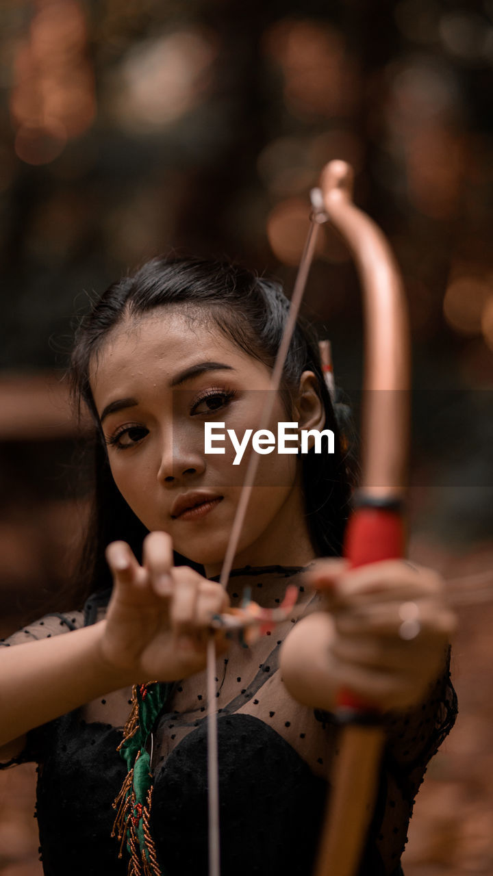 Portrait of woman shooting an arrow in the jungle