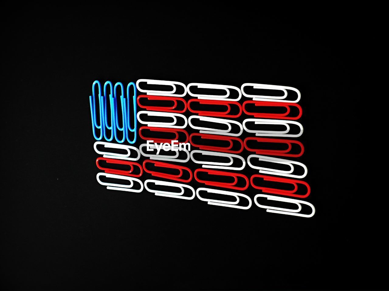 Red with blue and white paper clips against black background