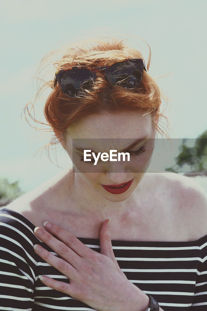 PORTRAIT OF YOUNG WOMAN AGAINST THE SKY