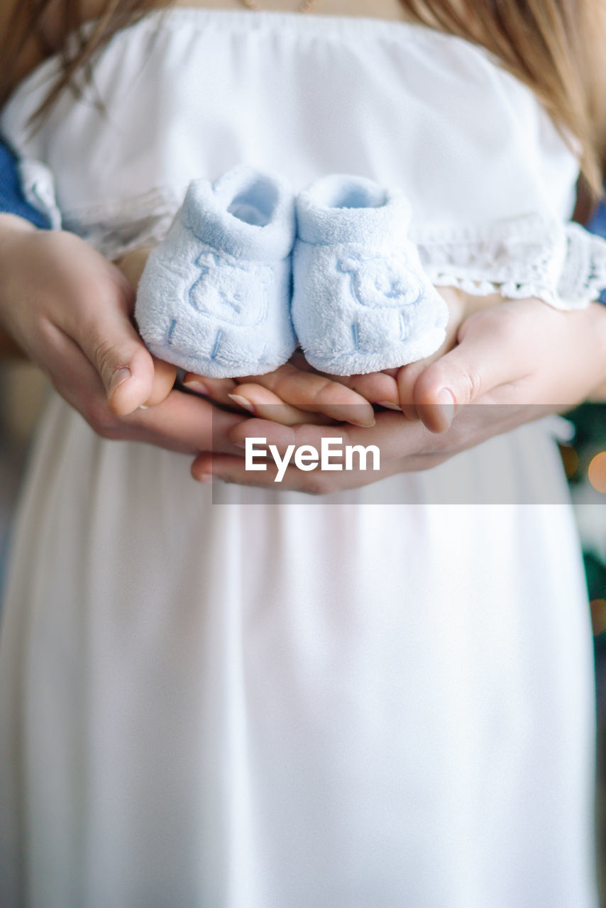 Midsection of woman holding baby booties