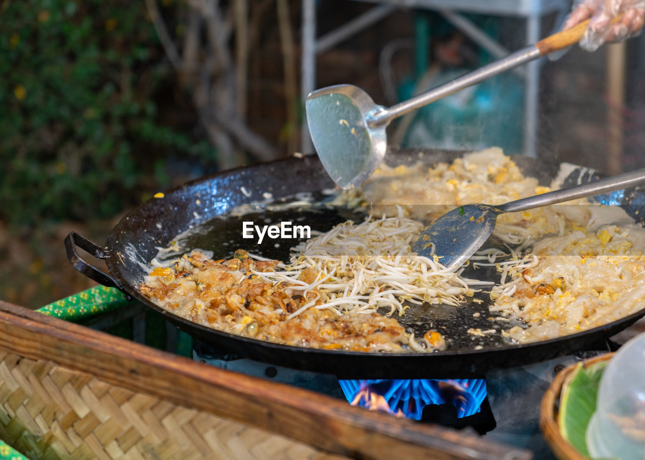 Chef cooking fried clams in big pan, thai food, street food