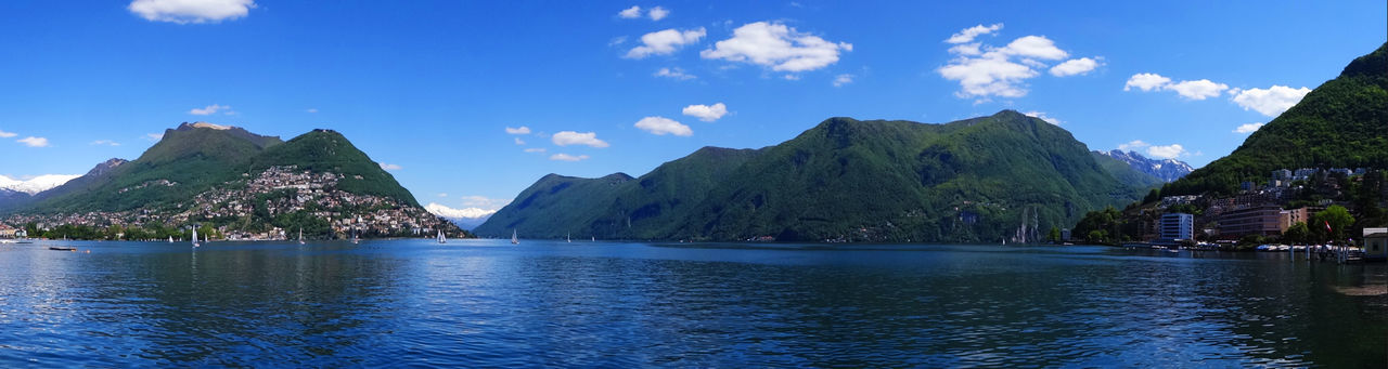 Panoramic view of sea and mountains against blue sky