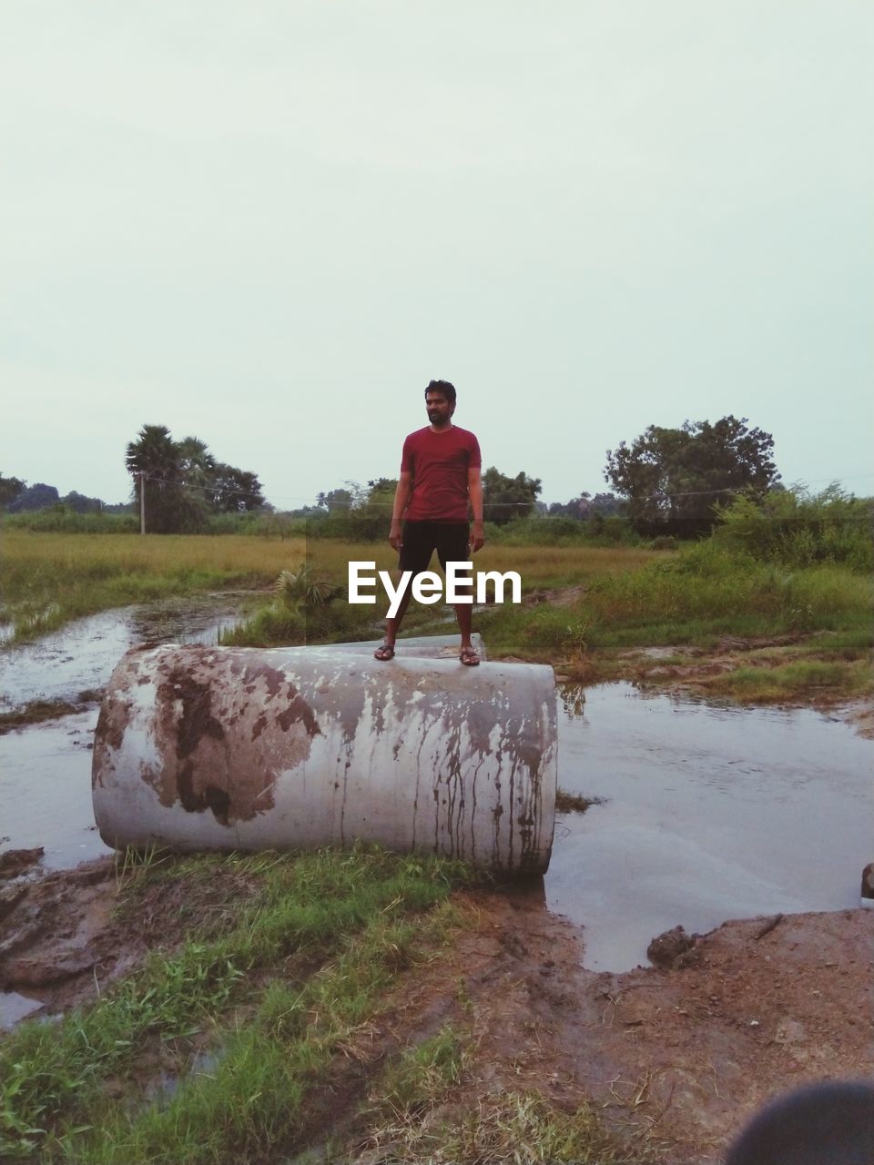 REAR VIEW OF YOUNG MAN STANDING ON LAND