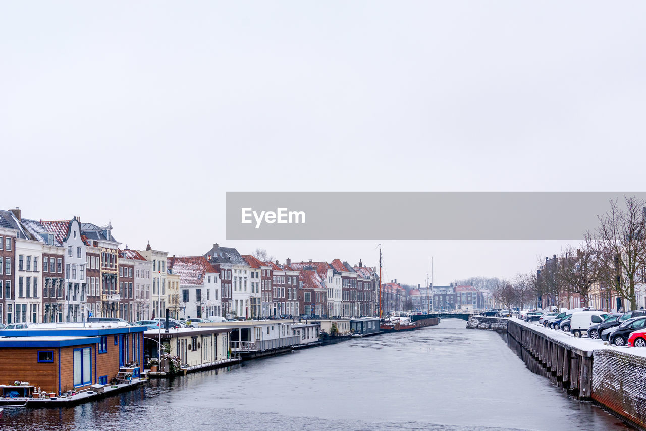 Canal amidst buildings in city against clear sky