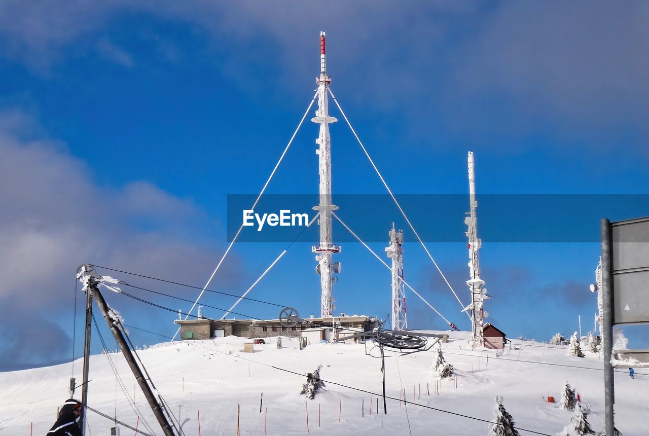 Low angle view of snowcapped mountain with radio relay against sky