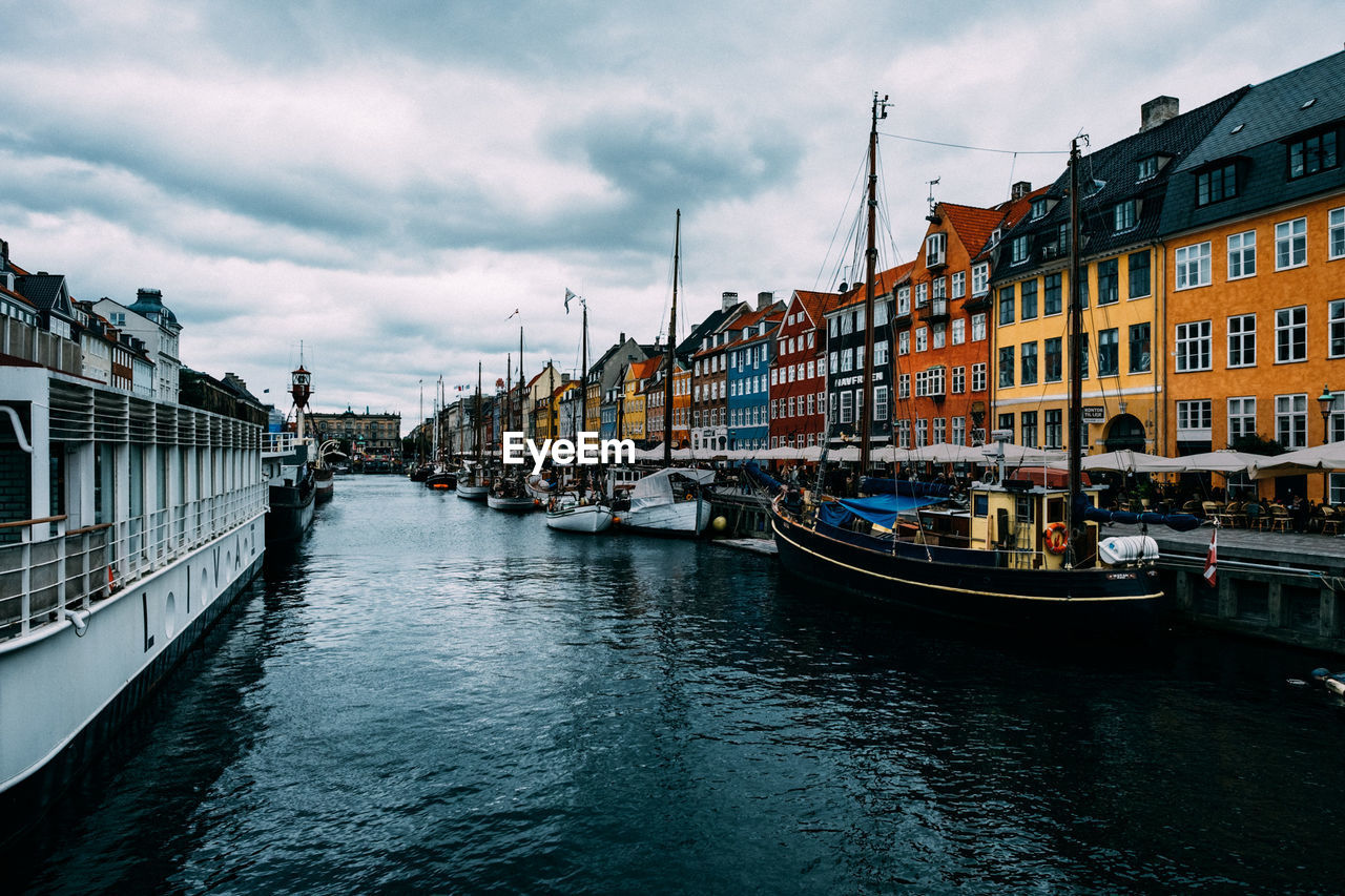 Boats moored in canal amidst buildings against sky