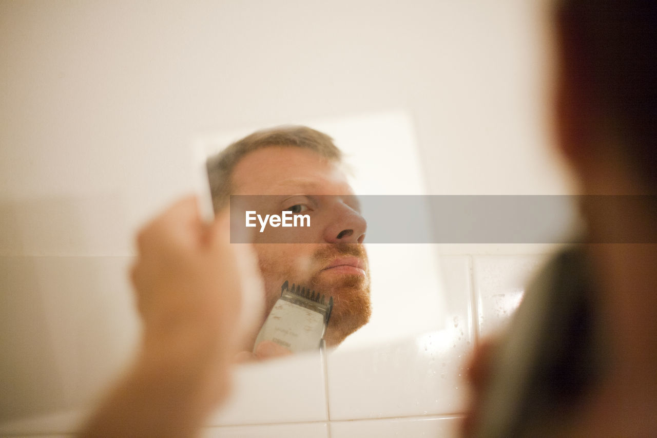 Man trimming beard in bathroom