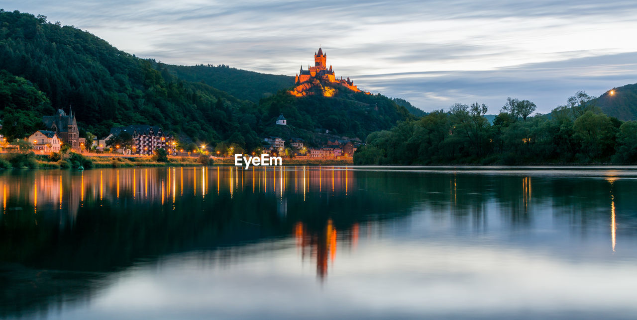 Scenic view of cochem imperial castle on mountain reflecting in river at dusk