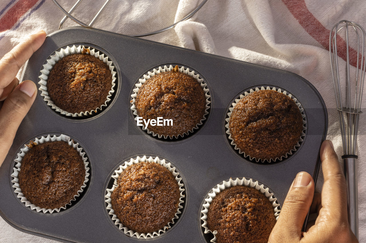 Top view of a tray full of homemade chocolate muffin cup cake held in hand