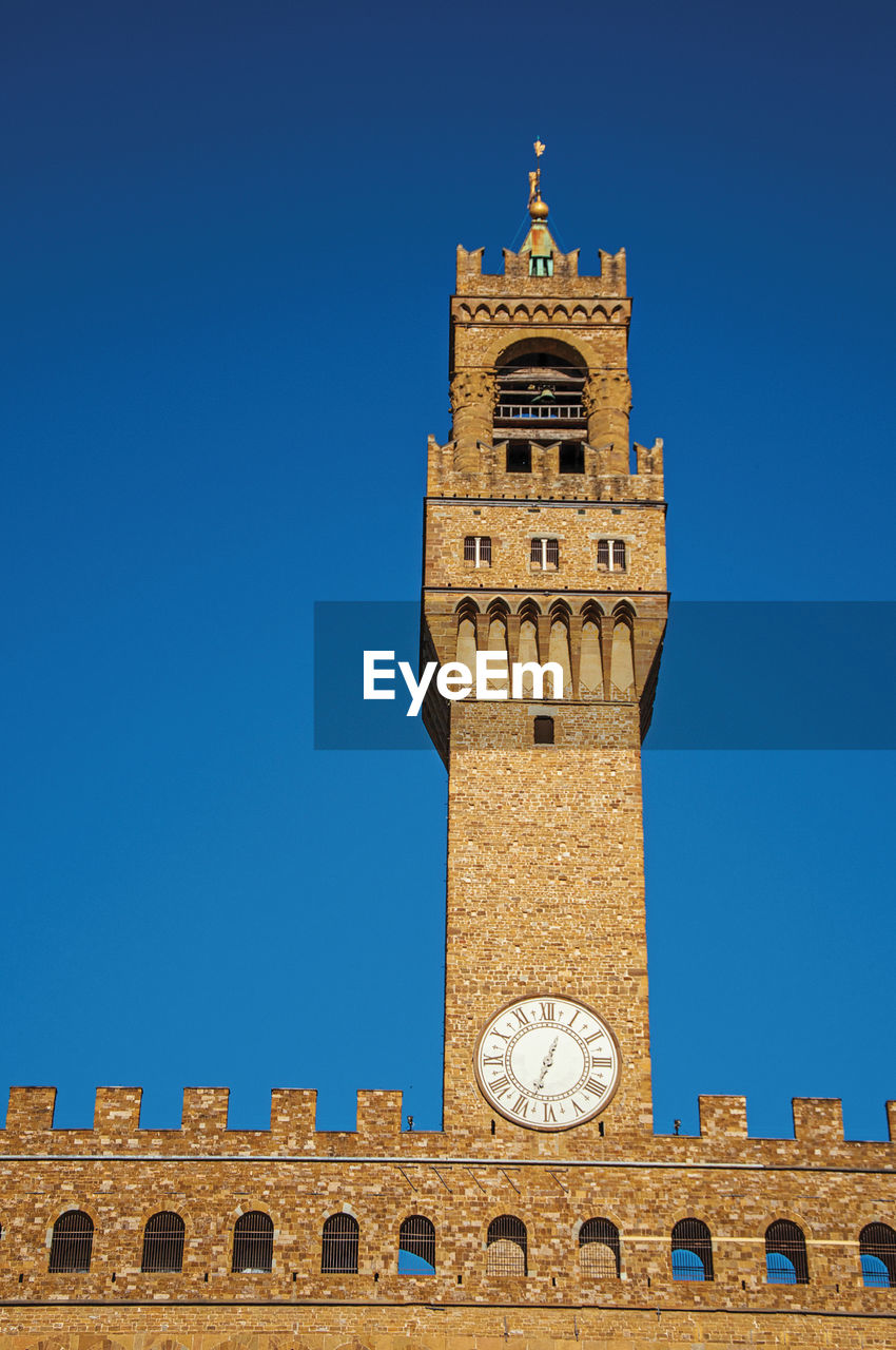 Tower with clock from the palazzo vecchio to the sunset. in the city of florence, italy.