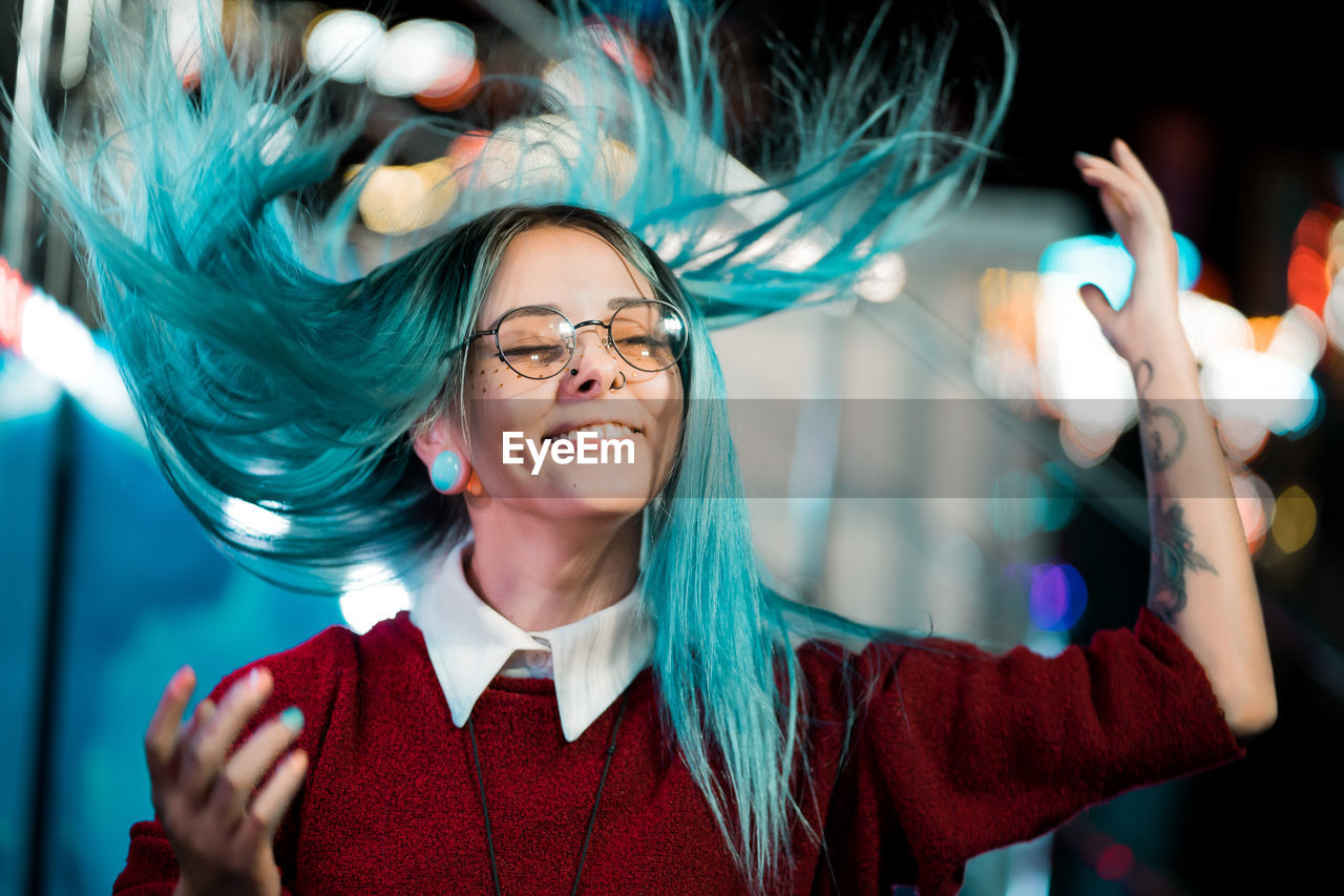 Happy woman with tousled hair gesturing at night