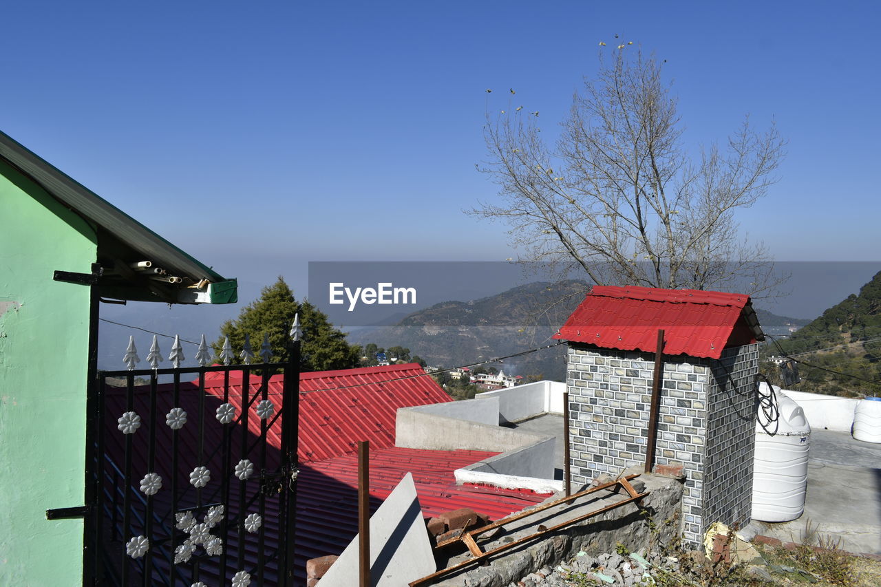 architecture, built structure, building exterior, house, sky, nature, building, no people, tree, mountain, plant, residential district, clear sky, day, outdoors, roof, blue, sunny, home, landscape