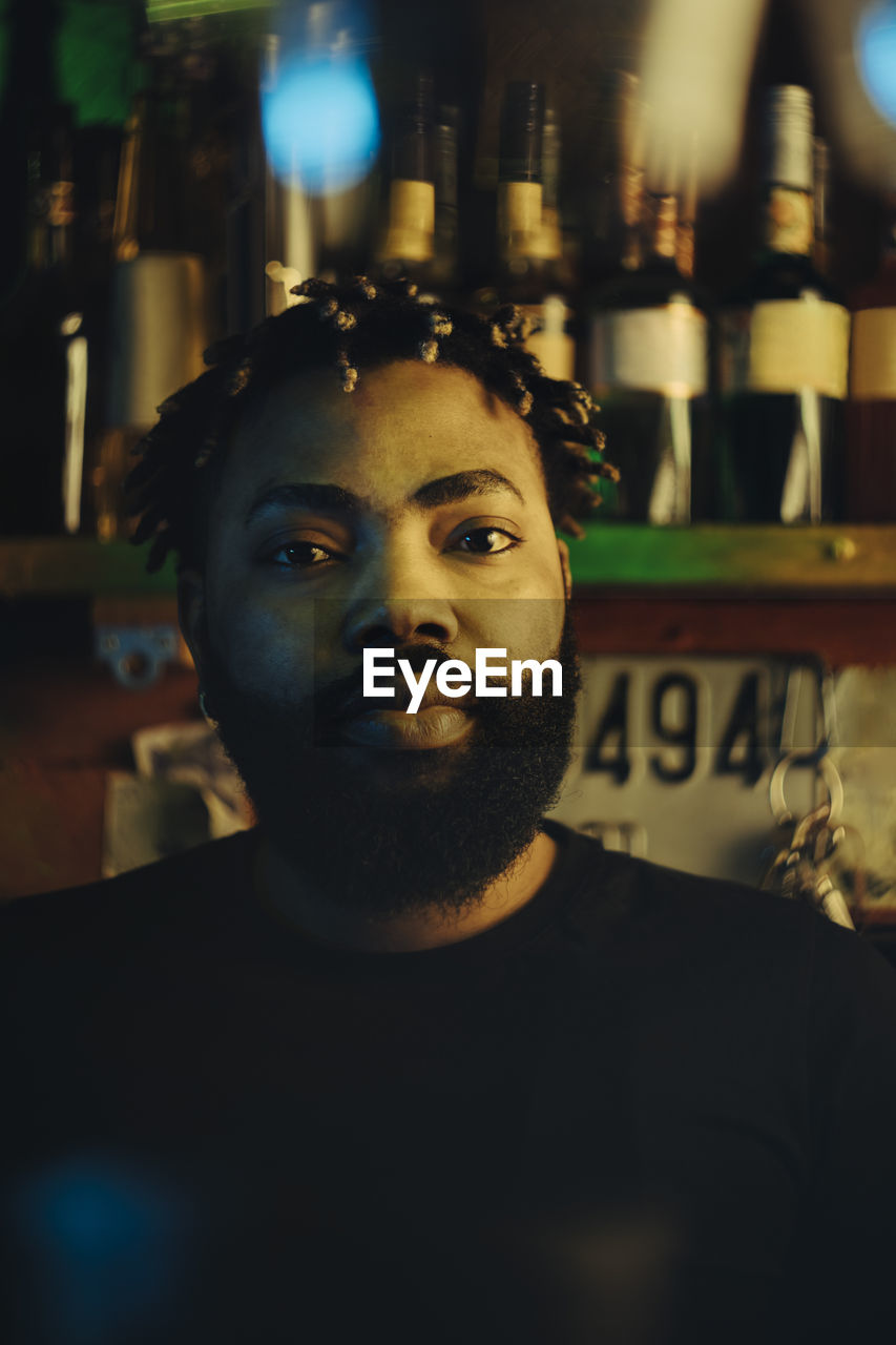 Portrait of young bearded bartender with afro hairstyle at bar