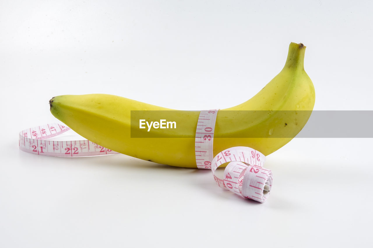 Banana with tape measure on white background