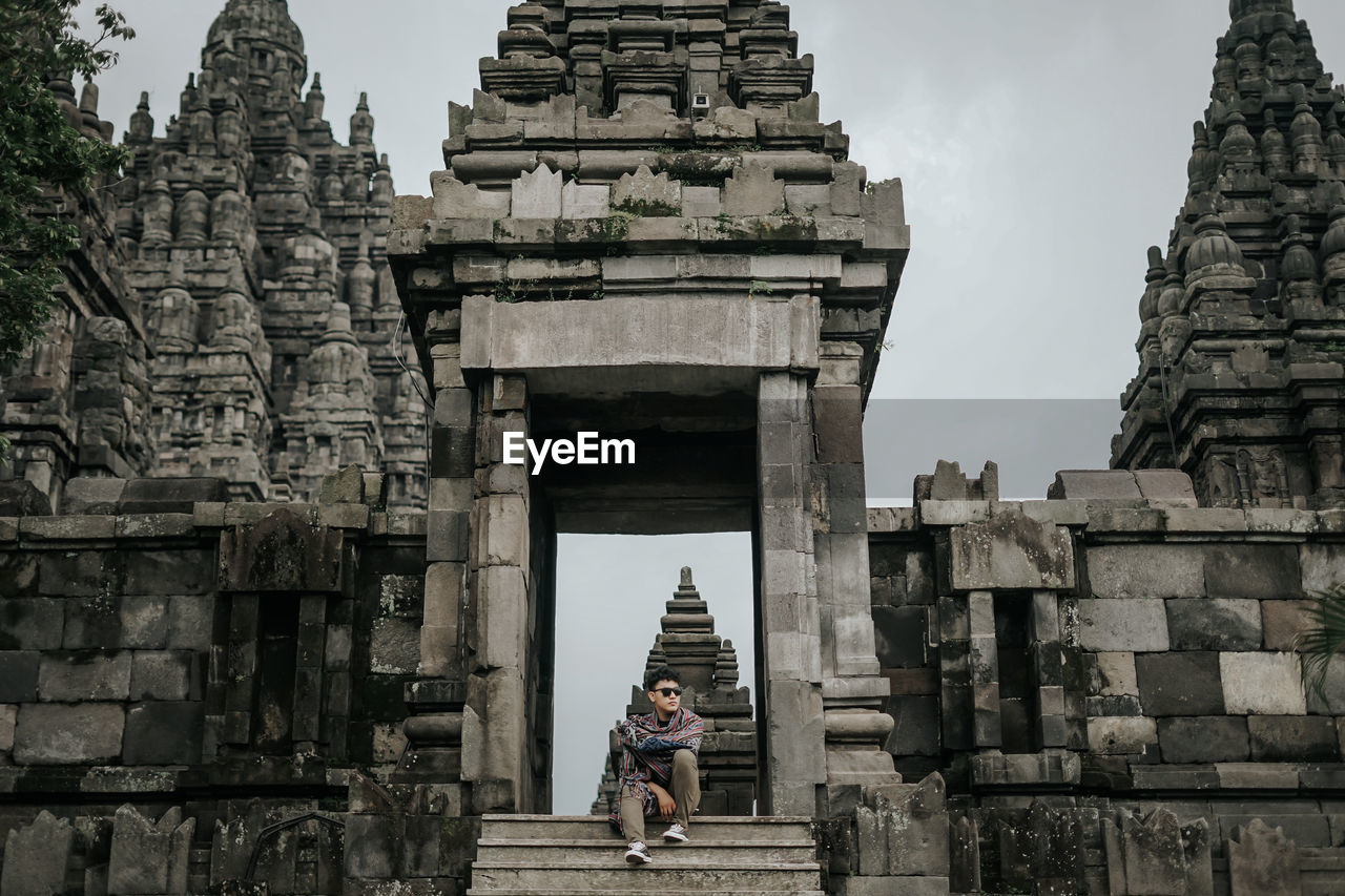 Low angle view of man sitting on staircase of temple