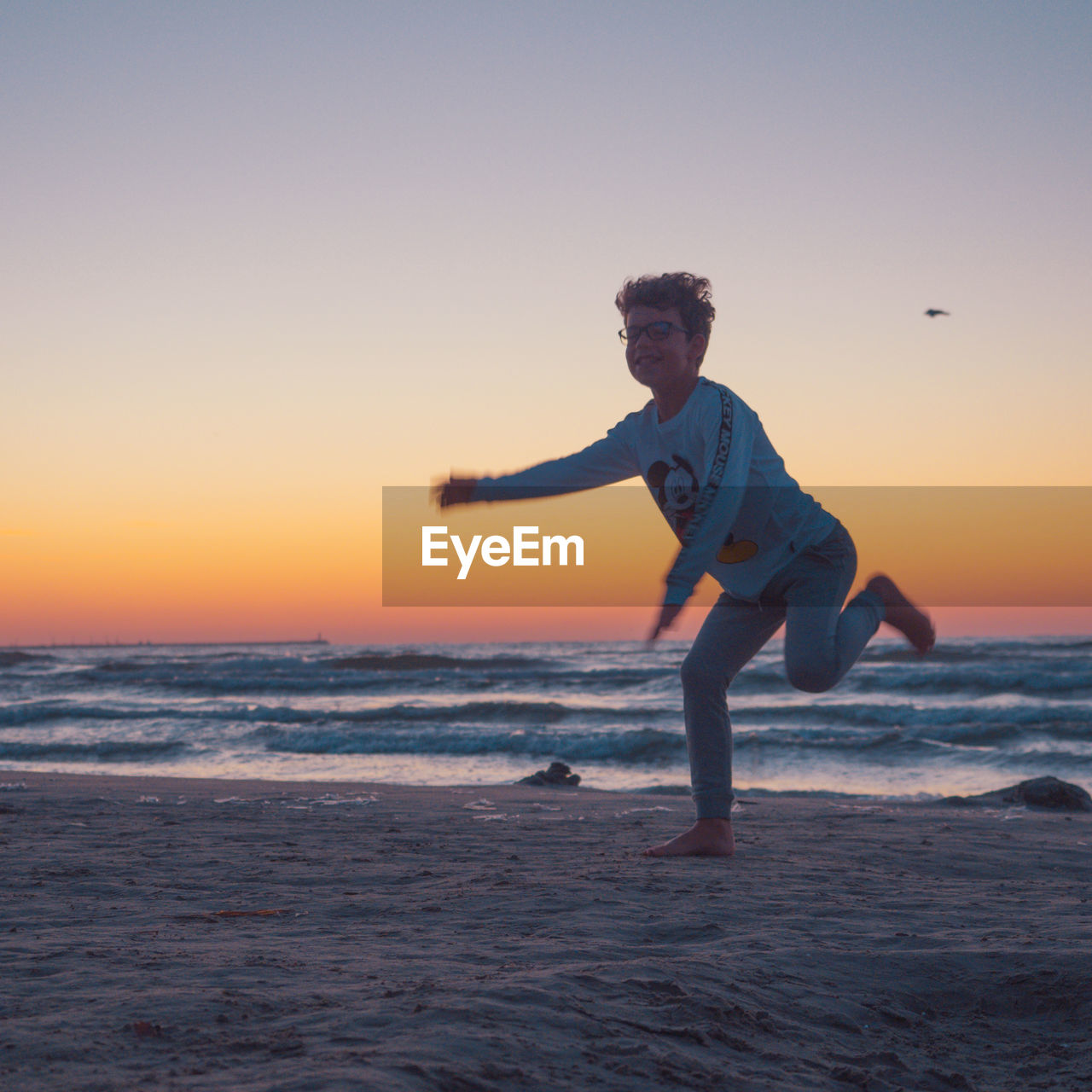 MAN ON BEACH AGAINST SKY DURING SUNSET