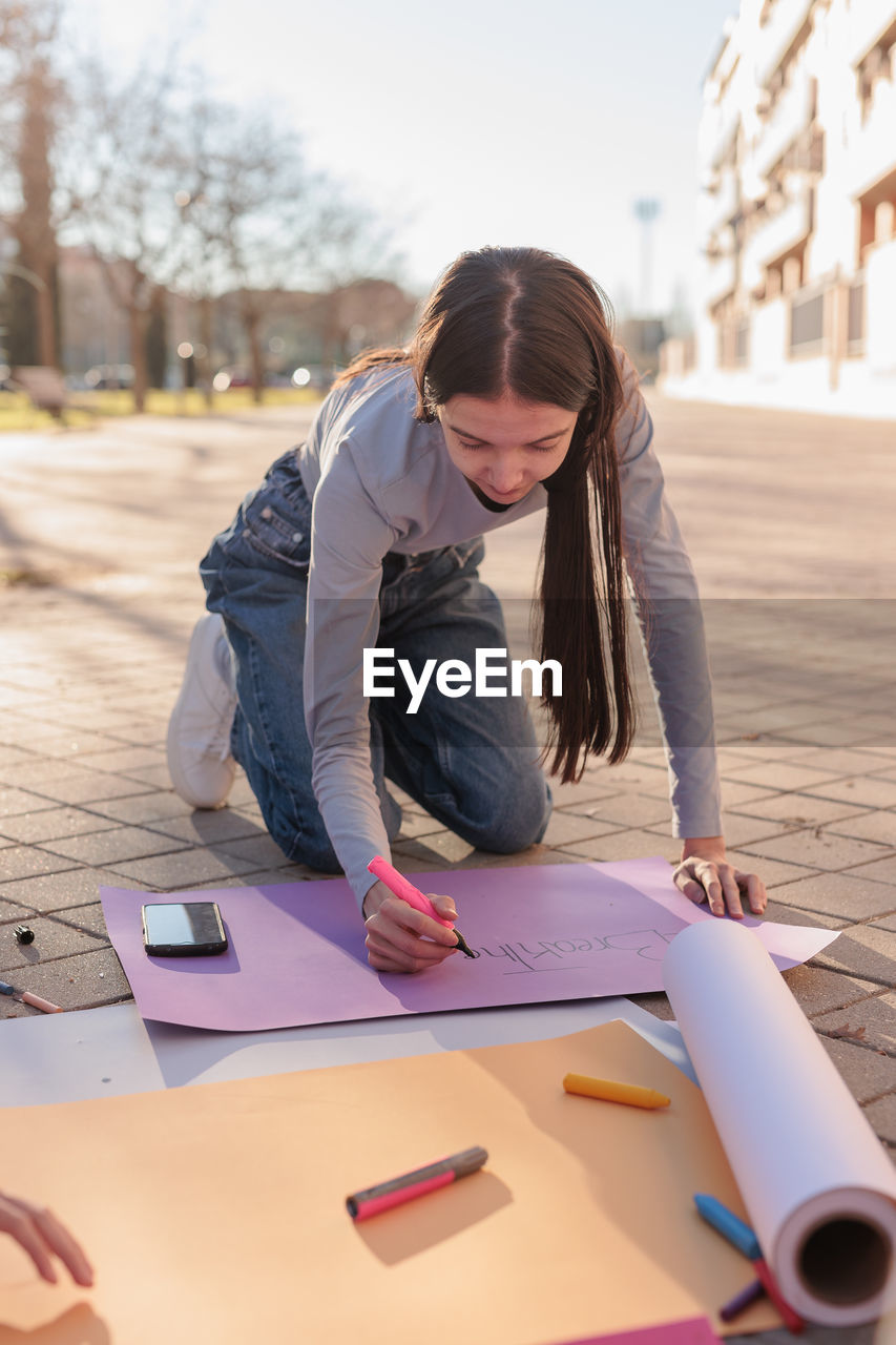 Young woman writing on banner outdoors