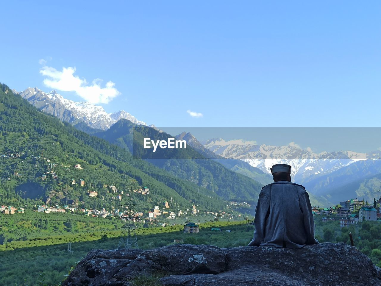 Rear view of man looking at mountains against sky