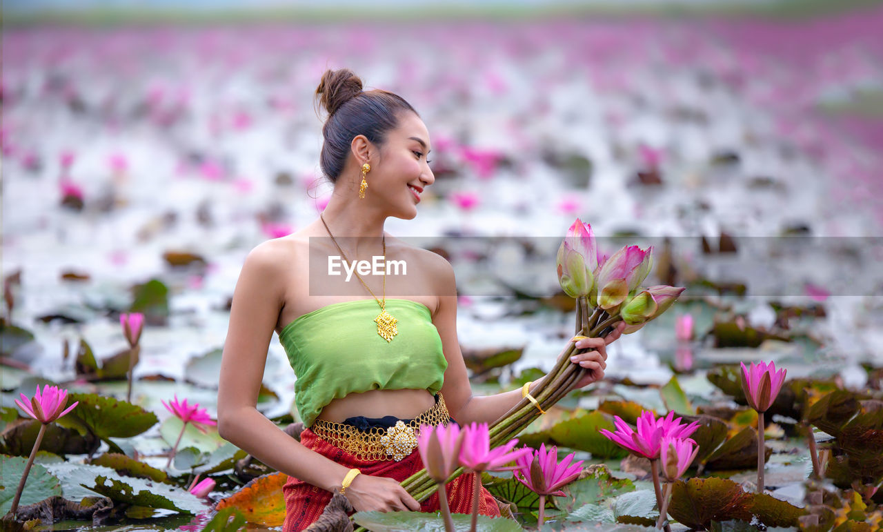 Woman holding pink flower in lake