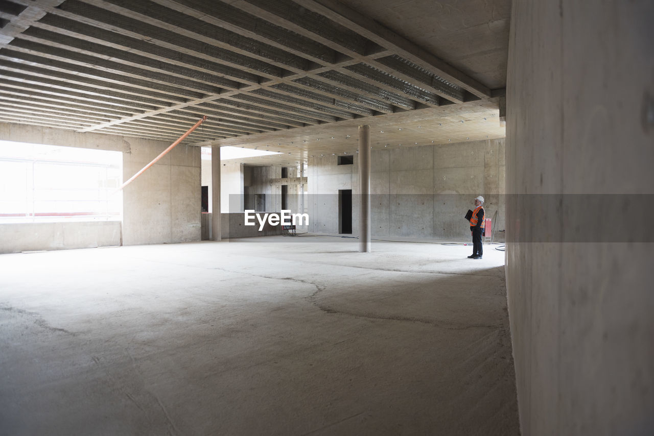 Man wearing safety vest looking around in building under construction