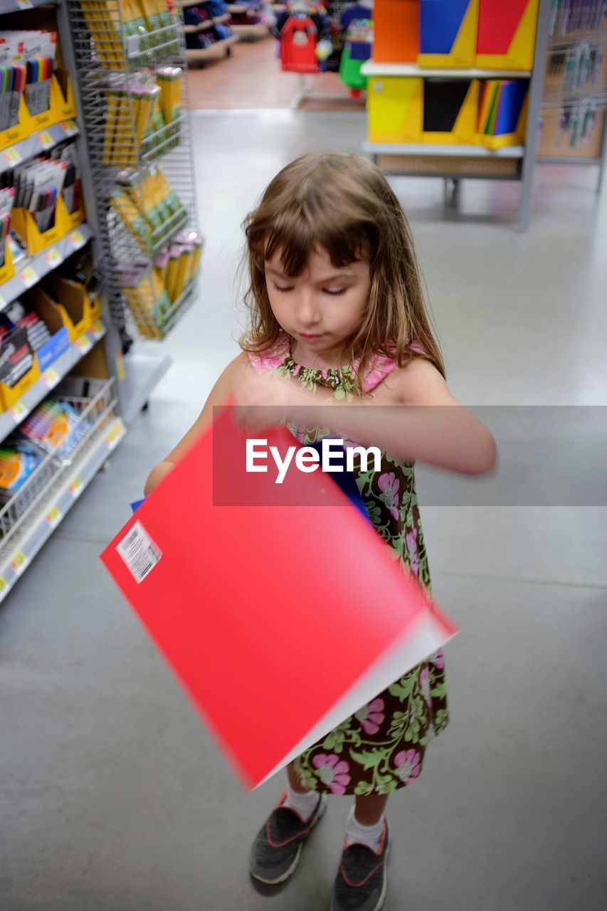 Cute girl holding file while standing in store