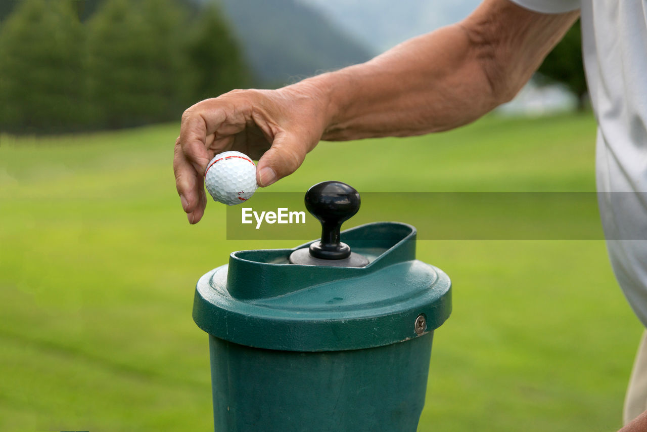 Close-up of man holding golf ball against blurred background