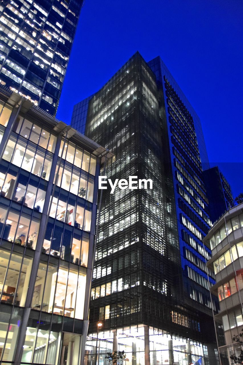 LOW ANGLE VIEW OF ILLUMINATED BUILDINGS AGAINST CLEAR SKY AT NIGHT