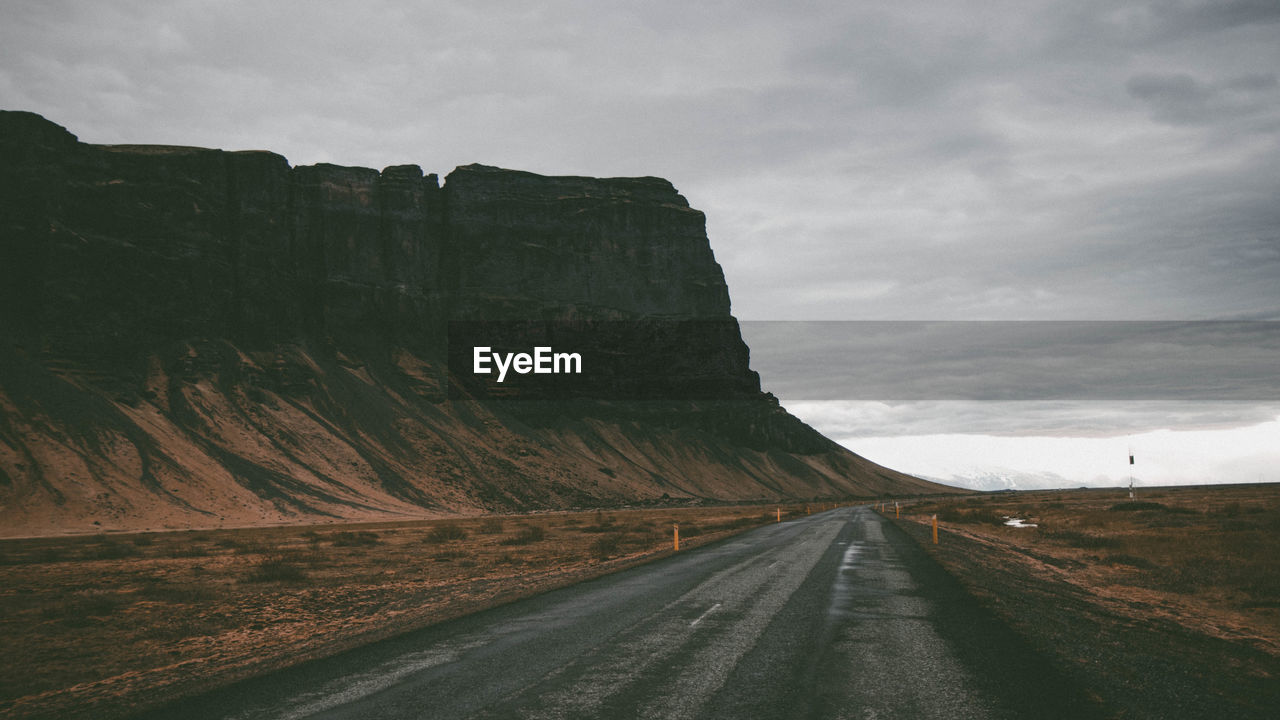 Road leading towards mountains against sky