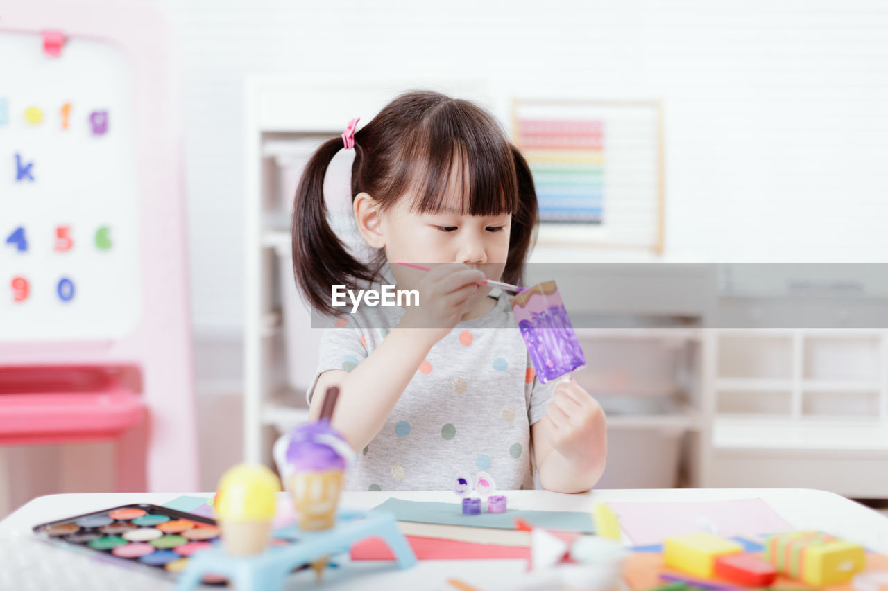 Young girl decorating hand made craft for homeschooling