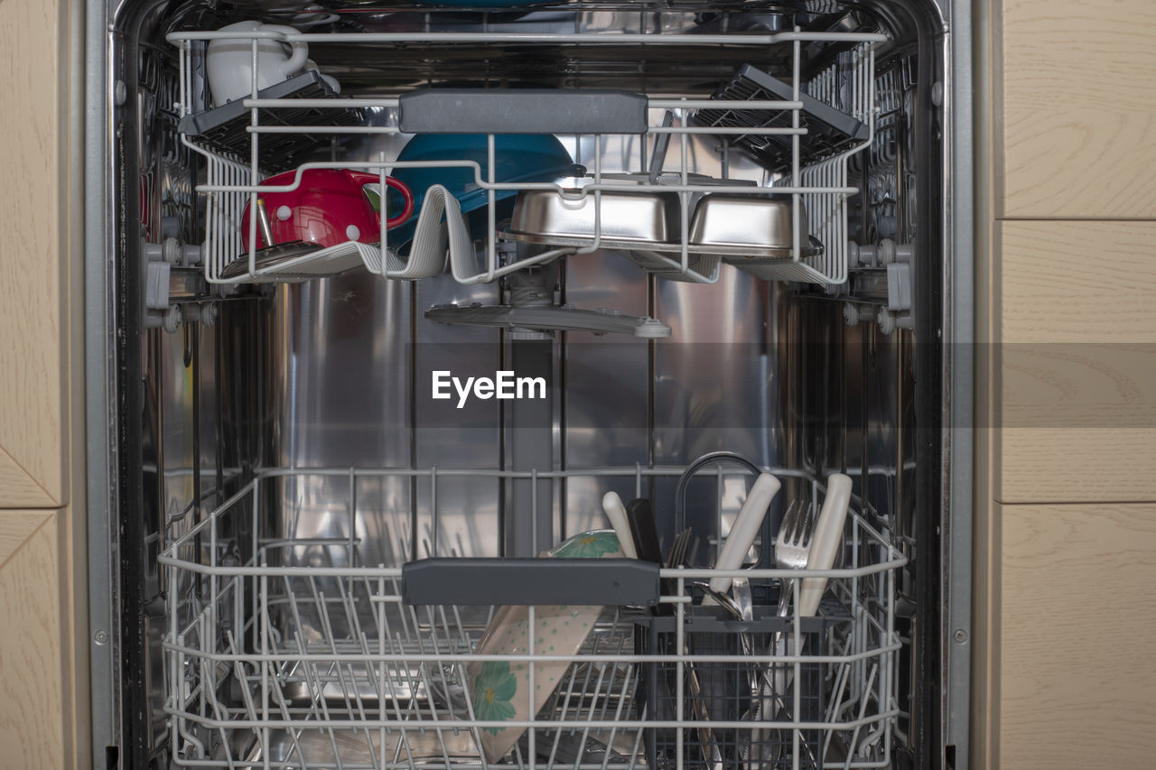 Closeup of the interior of a dishwasher loaded with plain white dishes.