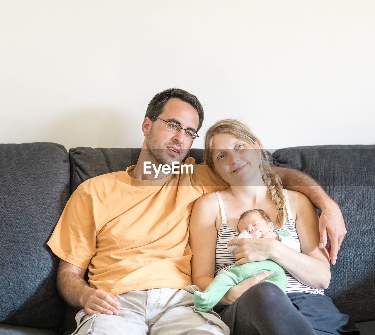 Happy mother and father holding baby at sofa at home