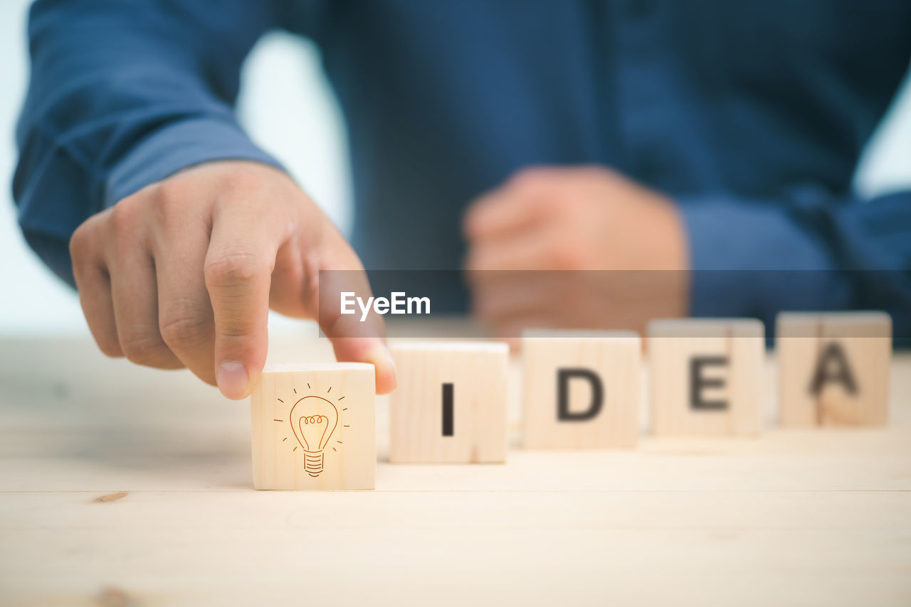 Midsection of man arranging letter blocks on table