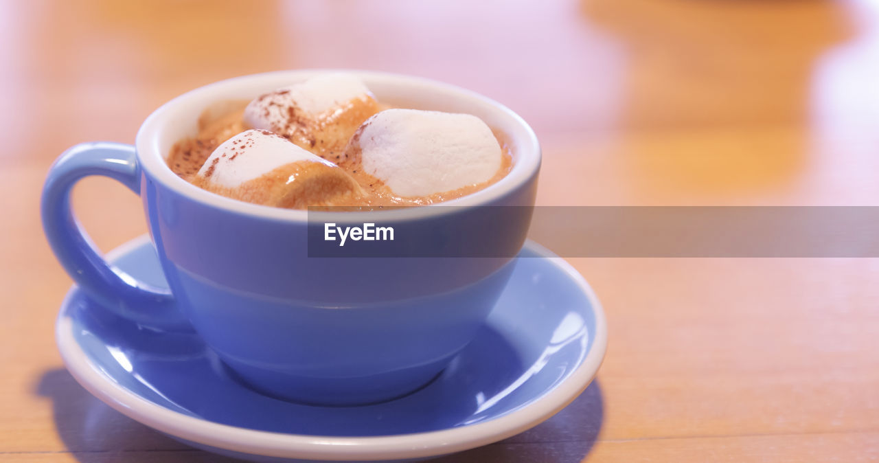 CLOSE-UP OF COFFEE CUP AND SPOON ON TABLE